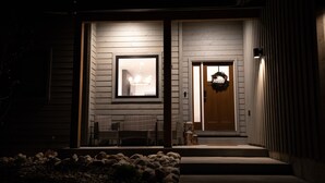 A house with a porch, a bench, and a door with a wreath.