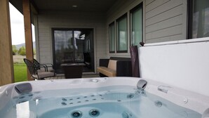 A hot tub with a view of a patio area and a house in the background.