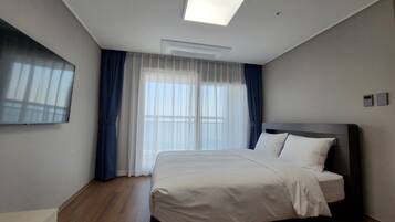 A modern hotel room with a large bed, a flat-screen TV, and a skylight.