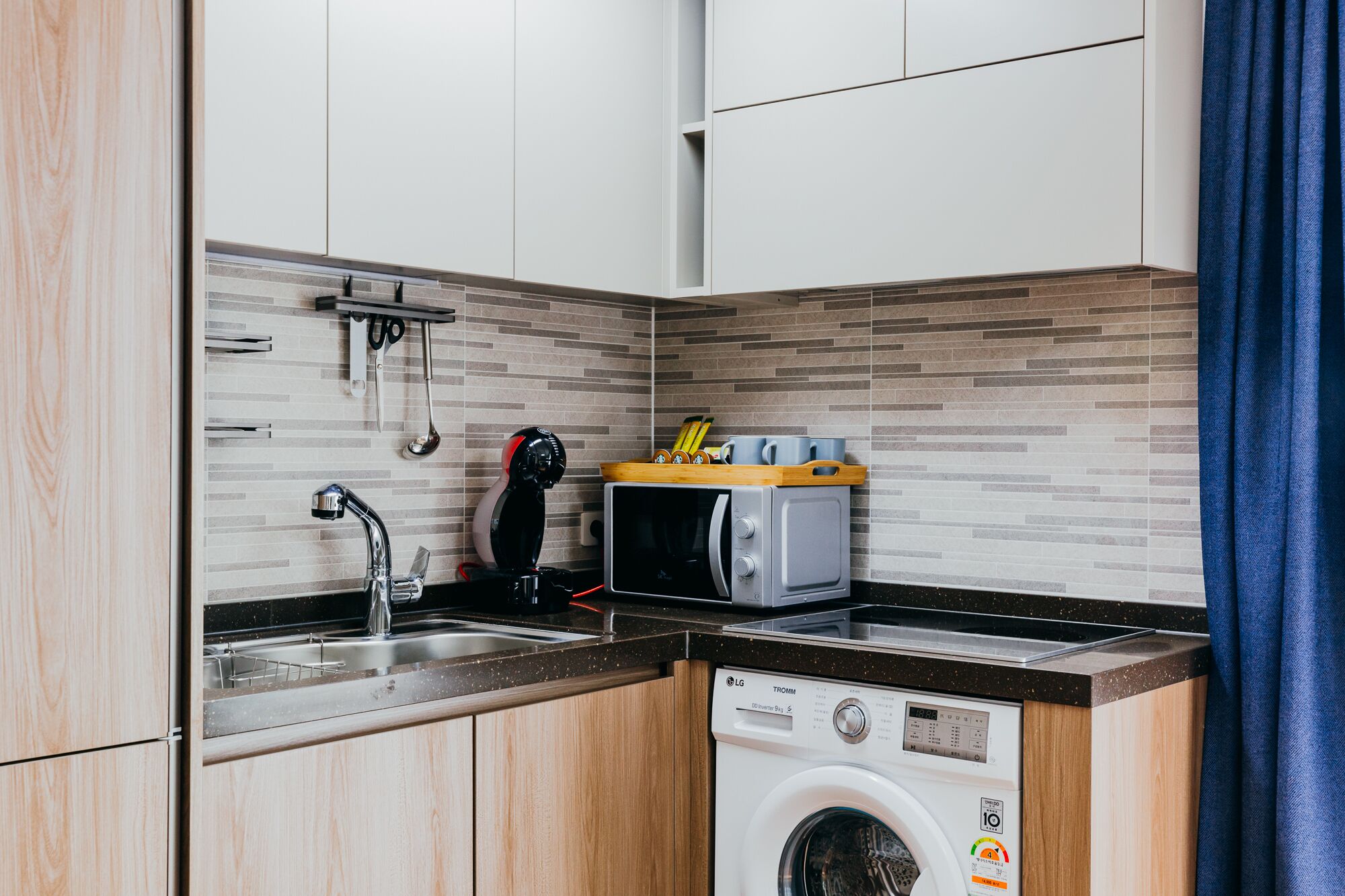Een kleine keuken met een wasmachine, een magnetron en een spoelbak.