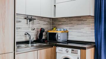 Een kleine keuken met een wasmachine, een magnetron en een spoelbak.
