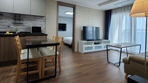 A modern living room with a dining area, a TV, and a kitchen. - Risen Oceanpark Hotel (Sokcho)
