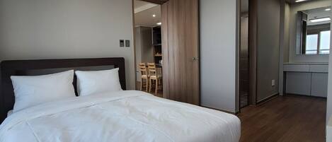 Quarto moderno com uma cama grande, um closet espaçoso e um banheiro com espelho.