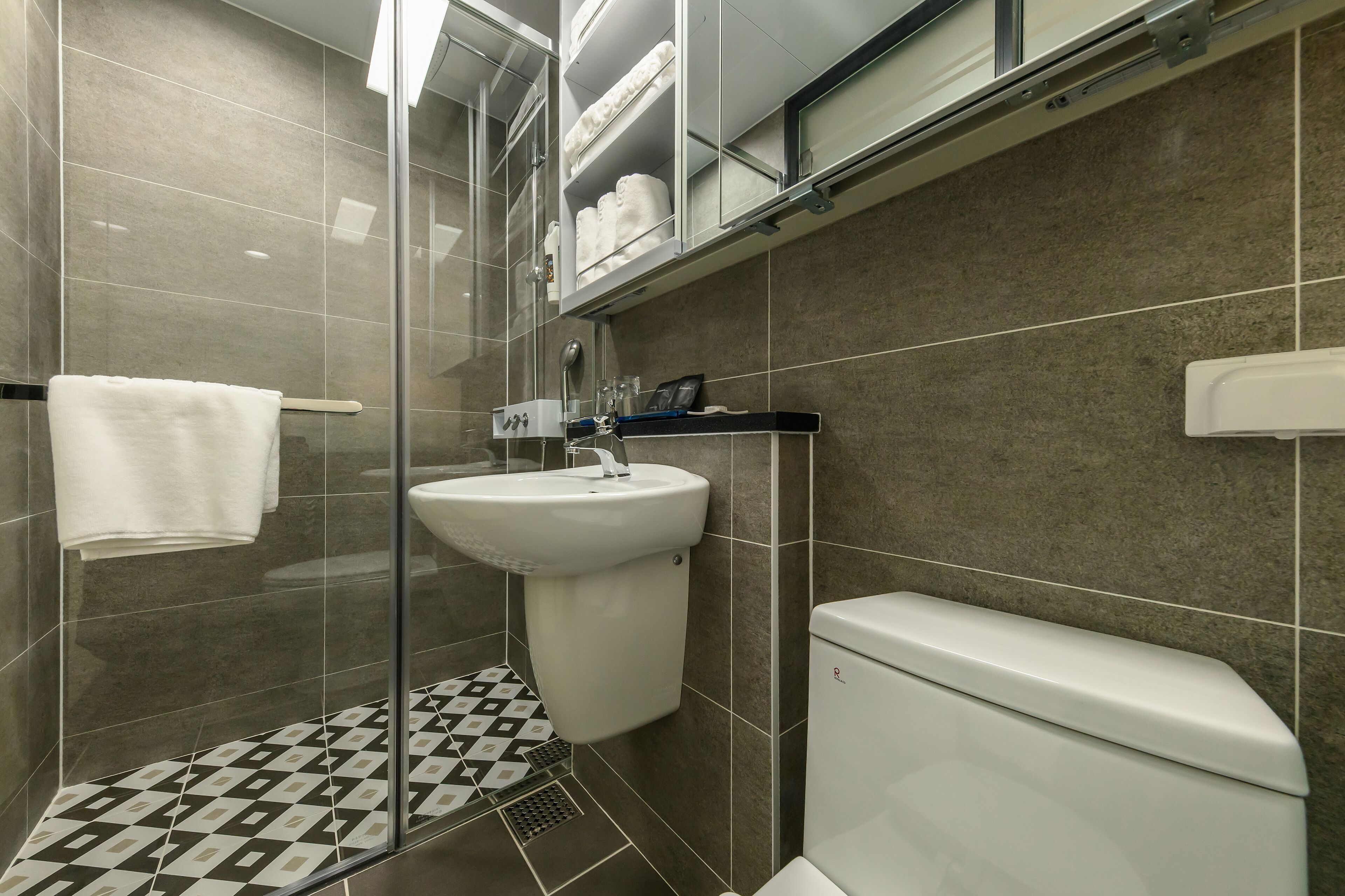 A modern bathroom with a glass shower enclosure, a white sink, and a toilet.