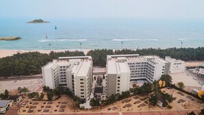A high-rise hotel with multiple floors, a parking lot, and a beach in the background. - Risen Oceanpark Hotel (Sokcho)
