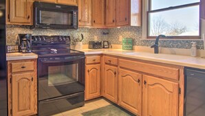 A kitchen with wooden cabinets, a black stove, a microwave, and a coffee maker. - 3 Mi to Boardwalk: Family Bethany Beach Home (Frankford)