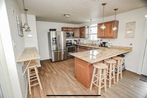 Enjoy cooking in this well-equipped kitchen with a central island, bar stools, and stainless steel appliances.