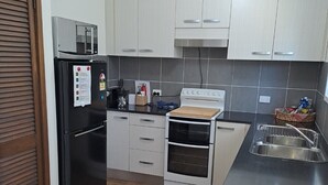 Eine moderne Küche mit weißen Schränken, einem schwarzen Kühlschrank, einem Herd und einer Mikrowelle.