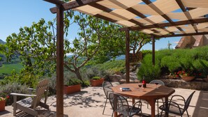 An outdoor patio with a wooden pergola, a table with chairs, and potted plants. - Relaxing hillside family accommodation with pool (Perugia)