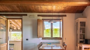 A dining area with a wooden table, chairs, a window with an open shutter, and a ceiling fan. - Relaxing hillside family accommodation with pool (Perugia)