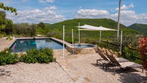 Ein Pool mit Whirlpool, umgeben von einer Steindeck und einer weißen Markise.