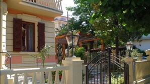 A residential building with a gated entrance, a balcony, and a garden area with potted plants. - Petit Chateau - Room with kitchen (Montecatini Terme)