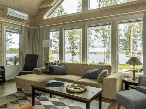 A spacious living room with a large window, a sofa, a coffee table, and a lamp.