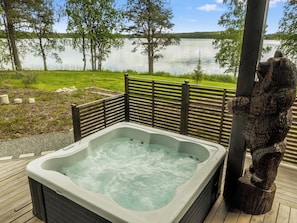 Un jacuzzi en una terraza de madera con vista a un lago y árboles.