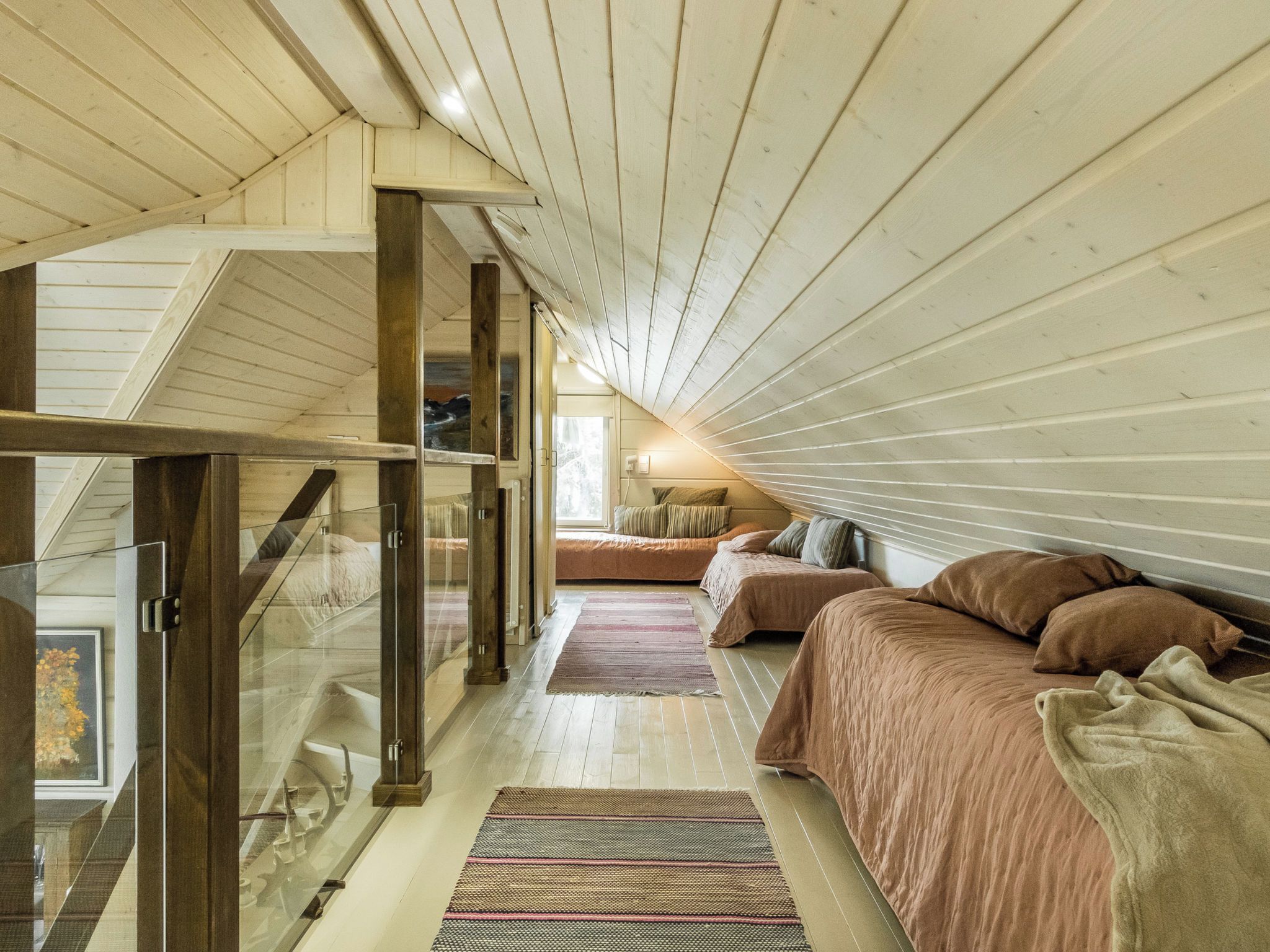 A bedroom with a sloped ceiling, a glass door leading to a balcony, and a bed with a striped blanket.
