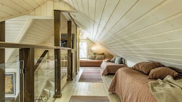 A bedroom with a sloped ceiling, a glass door leading to a balcony, and a bed with a striped blanket.