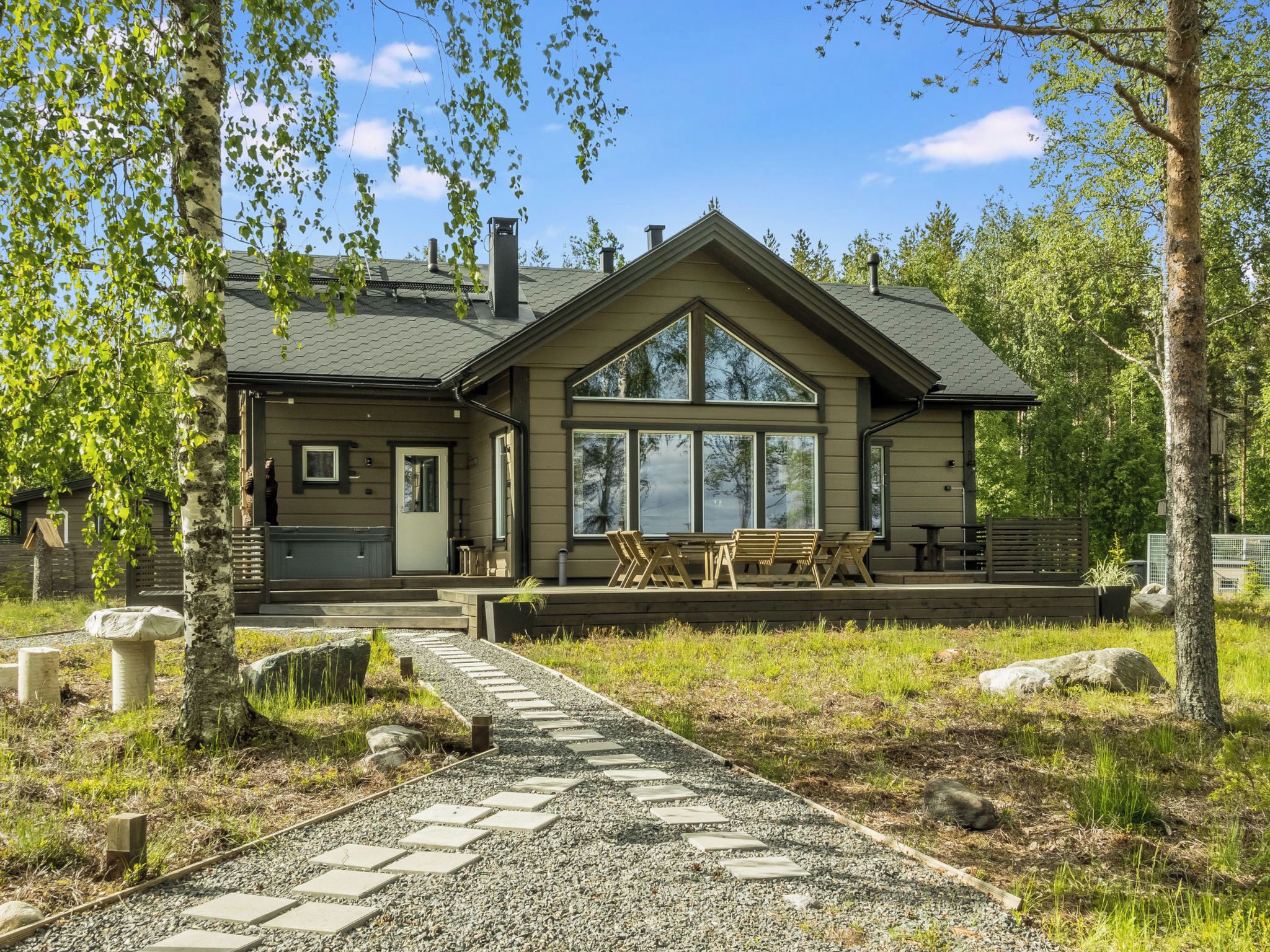 A cabin with a large front porch, a covered patio, and a gravel pathway leading to the entrance.
