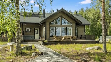Une cabane dotée d’une grande véranda à l’avant, d’un patio couvert et d’un chemin de gravier menant à l’entrée.