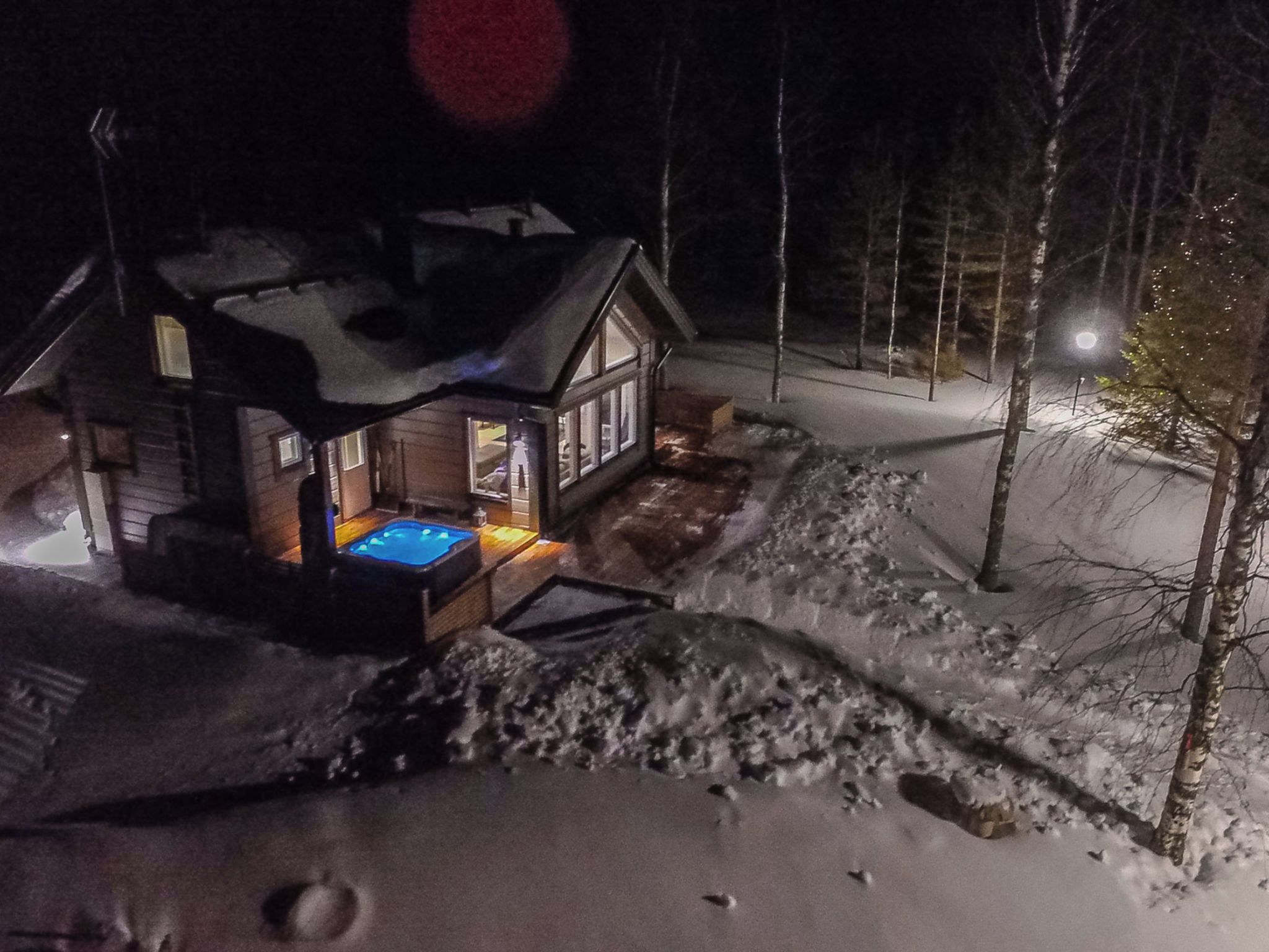 A cabin with a hot tub, surrounded by snow, and a small deck.