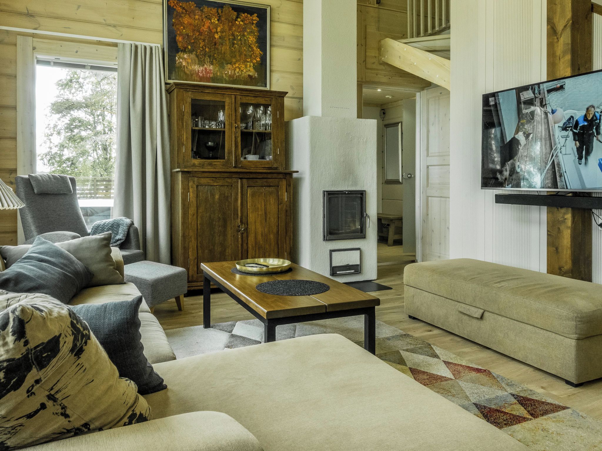 A cozy living room with a sofa, armchair, and a television mounted on the wall.