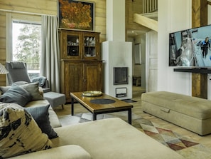 Una sala de estar acogedora con un sofá, un sillón y un televisor montado en la pared.