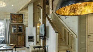 A spacious living room with a wooden dining table, a fireplace, and a staircase leading to an upper level.