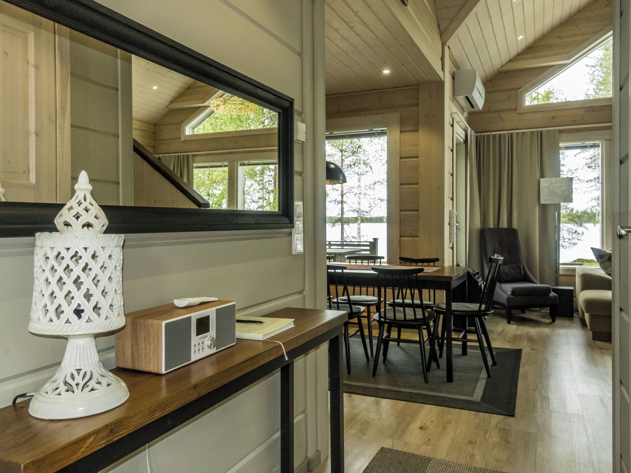 A modern interior with a wooden dining area, a large mirror, and a white decorative lamp.