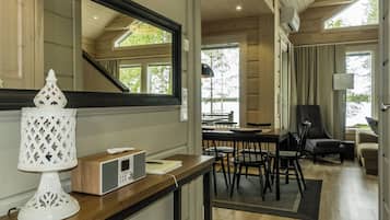 Un intérieur moderne avec un coin repas en bois, un grand miroir et une lampe décorative blanche.