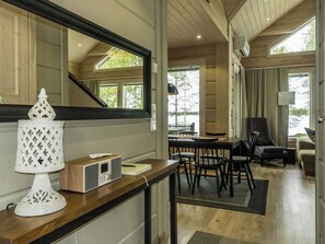Un interior moderno con una zona de comedor de madera, un espejo grande y una lámpara decorativa blanca.