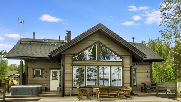 A two-story building with a large front porch, a chimney, and a deck with outdoor seating.