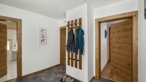 Um corredor com portas de madeira, um cabideiro com casacos e um par de sapatos em um descanso.