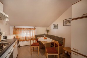 Une cuisine de taille réduite comprenant une table à manger, des chaises et un réfrigérateur.