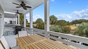 Un'area esterna coperta con un tavolo e sedie in legno, un barbecue e ventilatori a soffitto.