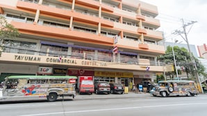 Un immeuble à plusieurs étages dont le rez-de-chaussée abrite un centre commercial comprenant une pharmacie et une épicerie.