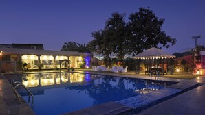 En swimmingpool med frit udsyn over det omkringliggende område, inklusive en bygning med en overdækket terrasse og udendørs siddepladser.