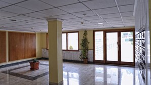 Un hall d’entrée spacieux, doté d’un sol carrelé, de meubles en bois, d’une plante en pot et d’une grande fenêtre donnant sur l’extérieur.