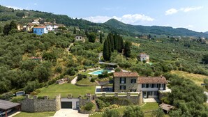 Eine Villa mit Swimmingpool, Steinmauern und Blick auf die umliegenden Hügel und Gebäude.