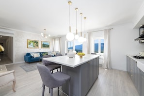 A modern kitchen with a central island, pendant lights, and a view of the mountains.