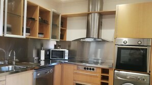 A compact kitchen with a dishwasher, microwave, oven, and built-in washing machine. - Bright duplex (La Línea de la Concepción)