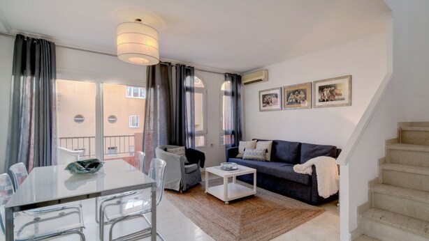 A modern living room with a dining area, a staircase, and a view of the outside. - Bright duplex (La Línea de la Concepción)