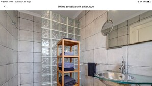 A bathroom with a glass shelf holding towels, a glass sink, and a tiled wall with a window. - Bright duplex (La Línea de la Concepción)