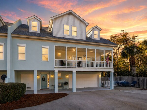 A two-story house with a balcony, garage, and a porch with seating.