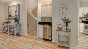 Una cocina moderna con armarios blancos, electrodomésticos de acero inoxidable y suelo de madera.