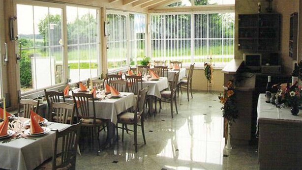 A dining area with tables set for a meal, large windows, and a fireplace.