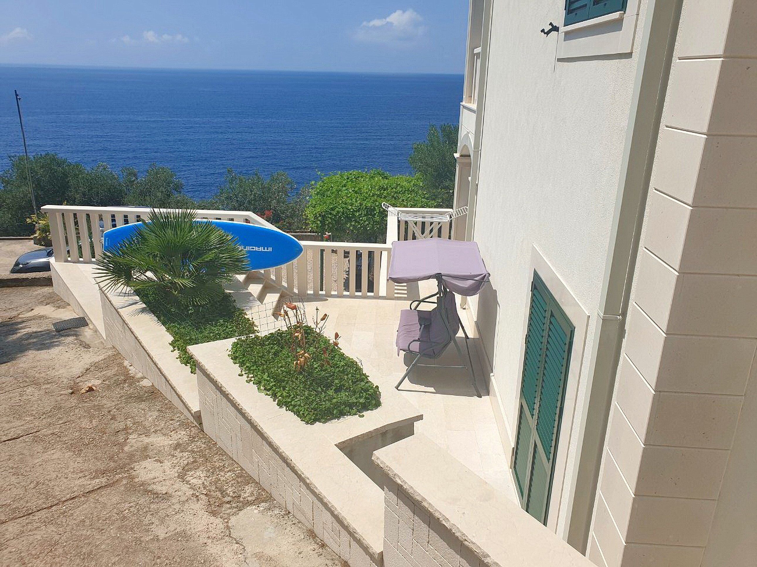 Ein Balkon mit Blick auf das Meer, ein blauer Pool und ein Tisch mit einem Stuhl.