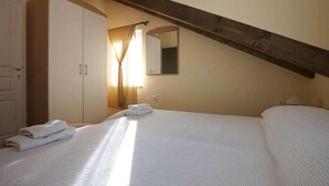 A bedroom with a large bed, a wardrobe, a mirror, and a sloped ceiling.