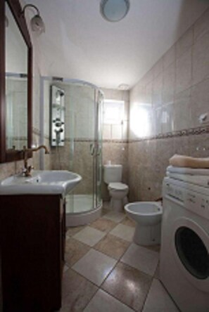 Une salle de bain équipée d’un lavabo, de toilettes, d’une douche et d’un lave-linge.