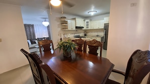 A dining area with a wooden table, chairs, and a plant centerpiece.