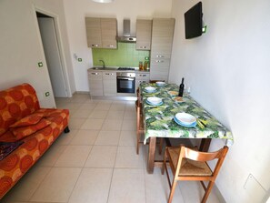 A dining area with a table set for four, a sofa, and a kitchen in the background.