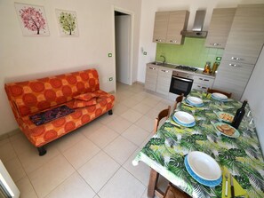 A modern kitchen with a dining table set for a meal, a sofa, and a small kitchen area.